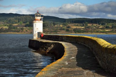 Eski deniz fenerine doğru boş bir gezinti, yakın plan. Arka planda kayalık kıyılar var. Dramatik mavi gökyüzü. Ardrishaig, İskoçya, İngiltere. Spor ve eğlence teması