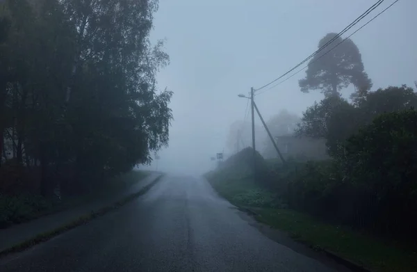 一个空旷的乡间柏油路穿过树林和村庄 在一个下雨天的大雾中 乌云密布的天空 公路旅行 — 图库照片