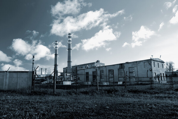 Industrial factory producing electricity with pipes against blue sky
