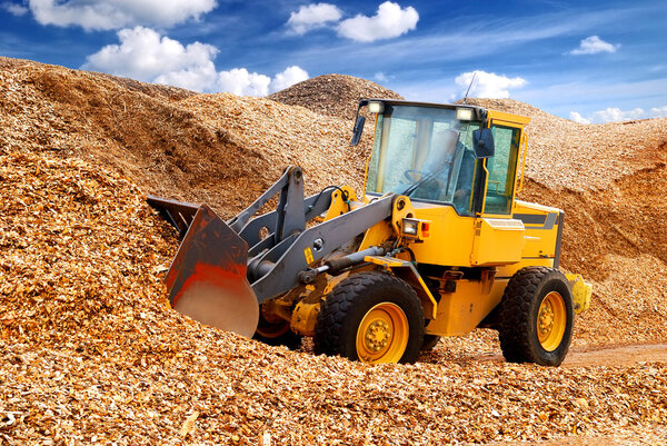 бульдозер работает в опилках
