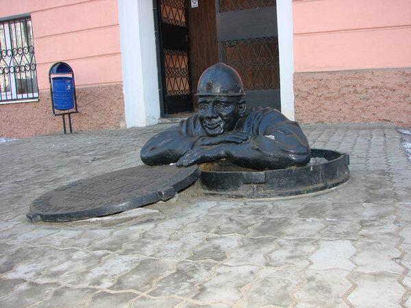 Yekaterinburg, Russia - February 27, 2012: Sculpture figure half man leaned out the hatch on his face - kindness and peace from the work done. On the hatch is written the name of the company and the year 1995. The sculptor is unknown.