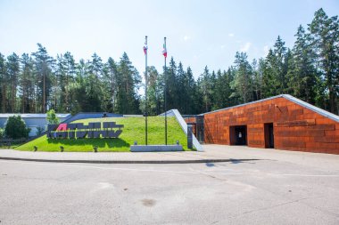 KATYN tepesinde büyük harflerle yazılmış bir yazı ve idam edilen Polonyalı ve Sovyet savaş esirlerinin isimlerinin yazılı olduğu bir duvar. Anıt kompleksi Katyn. Katyn köyü, Smolensk bölgesi. Çekim tarihi: 11 Temmuz 2020
