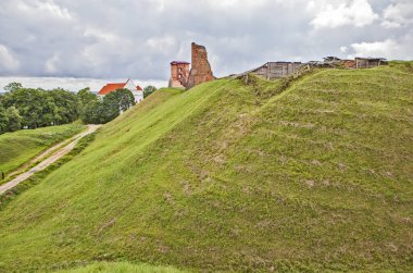 Bulutlu gökyüzünün altındaki yeşil tepede kırmızı tuğla kalıntıları