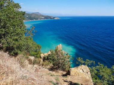 Deniz ve mavi gökyüzü ile kıyı kayaları ve yeşillik