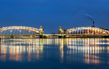 Köprü ve kıyıdaki binalar geceleri aydınlatılıyor. Saint Petersburg 'daki suları yansıtıyor.