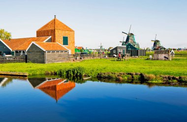 ZAANES-SCHANS, NETHERLANDS - 3 Mayıs 2018: İnsanlar rüzgâr tarlasıyla pitoresk etnoğrafya köyünde yürüyorlar