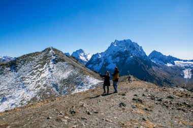 Turistler Mussa-Achitara ve Dombay-Ulgen dağlarının zirvelerinin arka planında fotoğraflanırlar. Dombay. Karachay-Çerkessia. Çekim tarihi: 7 Ekim 2020