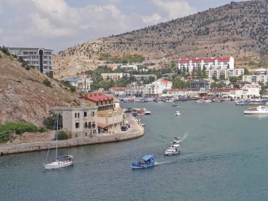 Balaklava limanında su üzerinde hareket eden insanlarla dolu gemiler. 