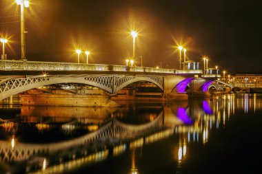 Duyuru Köprüsü ve kıyıdaki binalar gece aydınlandı. Saint Petersburg 'da sular yansıdı.