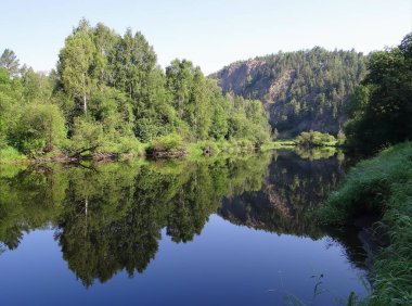 Yeşil ağaçlı ve mavi gökyüzü suya yansıyan tepe, Olenyi Ruchyi parkı, Bazhukovo, Rusya