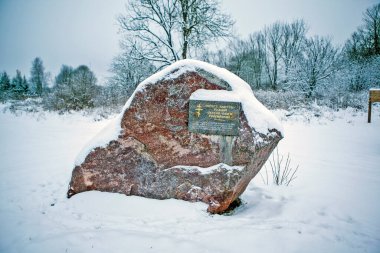 Tapınağın yanında bir anıt taşı (Vybuty 'nin Prenses Olga' nın doğum yeri olduğunu gösteren bir tablet ile). Vybuty kilisesinin avlusunda. Pskov bölgesi. - Rusya. Çekim tarihi 23 Aralık 2018