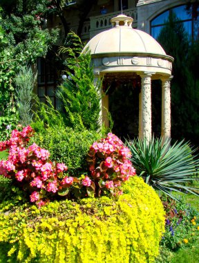 Parlak çiçeklerin arasında zarif bir çardak. Eski park. Kabardinka. Krasnodar bölgesi. Çekim tarihi: 3 Eylül 2011