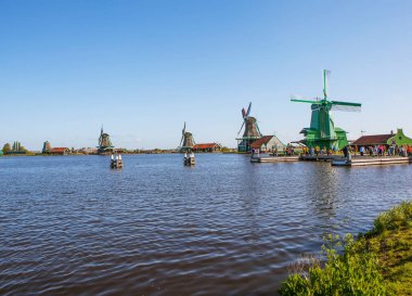 ZAANES-SCHANS, NETHERLANDS - 3 Mayıs 2018: İnsanlar rüzgâr tarlasıyla pitoresk etnoğrafya köyünde yürüyorlar
