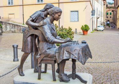 Sansepolcro. Kızına bobbin dokuması öğreten bir kadının sokak heykeli. İtalya. Çekim tarihi 5 Mayıs 2014