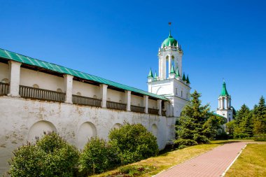 Manastır duvarında parlak güneş ışığı altında çan kuleleri var.