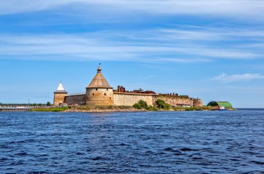 Güneş manzaralı Oreshek Kalesi bulutlu mavi gökyüzünün altında insanlarla aydınlandı