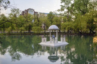 Kuğuların geri kalanı için gölette yüzen balkon botu. Central Park of Culture and Rest adını K.L. 'den almıştır. Khetagurov. Hughkavkaz, Kuzey Osetya, Rusya. 13 Mayıs 2021