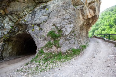 Dağda yapılmış bir tünel ve dağın etrafında eski bir yol. Digorskoe Boğazı. Kuzey Osetya. - Rusya. 17 Mayıs 2021
