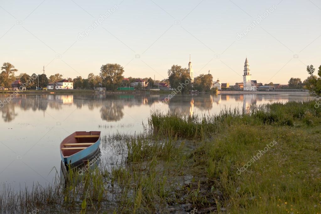 Nevyansk, Russia - July 3, 2014: The Rock, the white building on the shore of the pond. Right - tall, steepled tower with a slope to the left. Right - a building with a portico and columns at the entrance. And five domes on top.