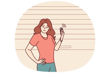 Kadın garaj kapısının yanında duruyor ve otomatik olarak girişi açmak ya da kapatmak için elektronik anahtar kullanıyor. Kız sürücü garajda poz veriyor. Arabayı güvenli bir şekilde depolamak ve kişisel araçları hırsızlıktan korumak için.