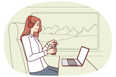 Tren yolcusu kadın, trende çalışırken dizüstü bilgisayar kullanıyor ve tren vagonunda büyük pencerenin yanında oturup kahve içiyor. Başarılı kulaklıklı kız gezgin trende oturup film izliyor.