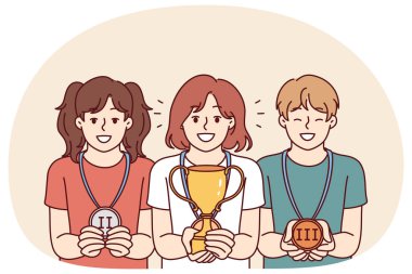 Okul olimpiyatlarını ya da yarışmaları kazandıkları için ödülleri olan çocuklar liderlik pozisyonlarına verilen ödüllere seviniyorlar. Kazanan kupa sahibi kız, madalya kazanan sınıf arkadaşlarının yanında duruyor.