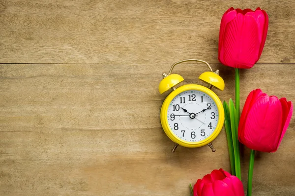 Clock nad tulips on wooden table. — Stock Photo, Image