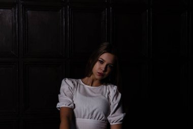 Kahverengi arka planda beyaz tişörtlü genç.