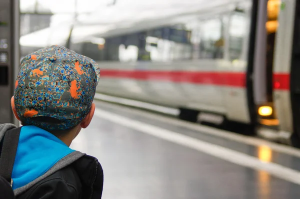 Çocuk bir kap ile tren demiryolu platformu üzerinde bekler.