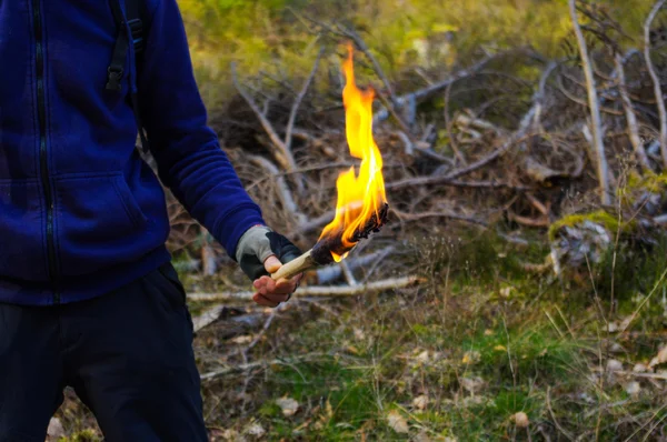 bir adam ve el ile meşale alevi vahşi doğa arka planda bir parçası.