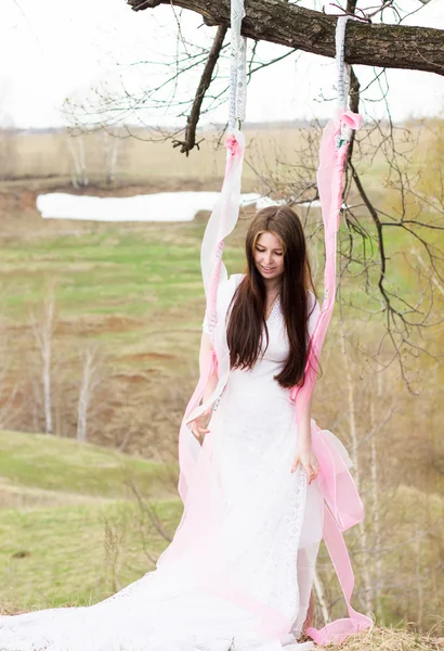 Belle femme dans toute robe de mariée blanche sur la journée ensoleillée swing en plein air — Photo