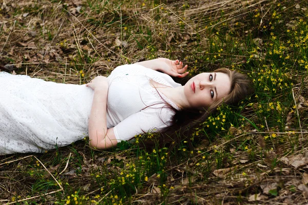 Krásná nevinná žena v bílých šatech, ležící na trávě — Stock fotografie