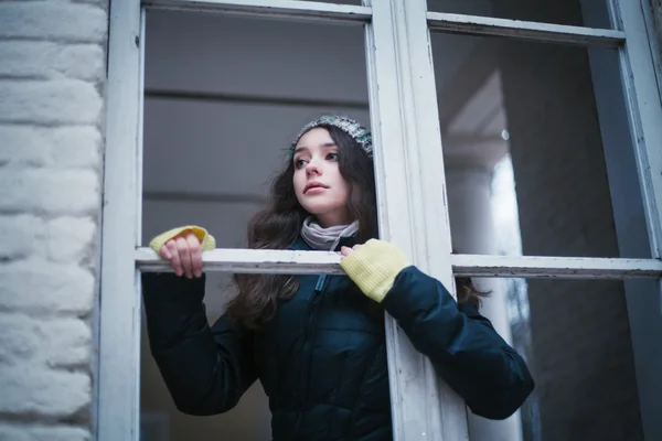 Mooie vrouw in de hoed op zoek door het raam — Stockfoto