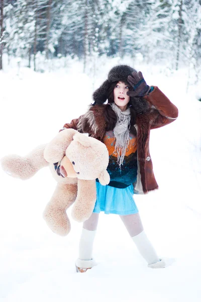 テディベアと雪に覆われた森林の背景に冬の美しい少女 — ストック写真