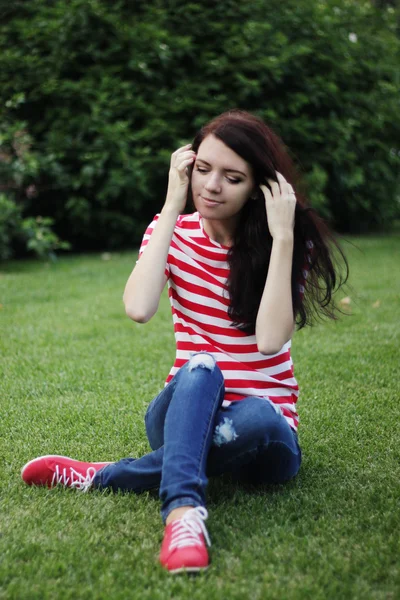 Onnellinen kaunis nainen istuu vihreällä kentällä kesällä — kuvapankkivalokuva