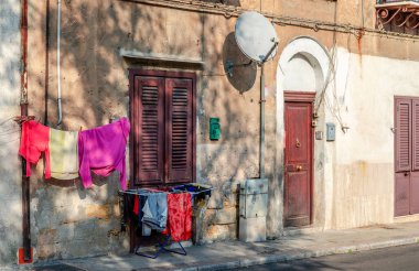 Sicilya 'nın başkenti Palermo' nun merkezindeki Via Cappuccini 'de asfaltta kirli çamaşırların asılı olduğu eski bir ev manzarası..