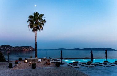 Gece deniz kenarında bir havuz. Palmiye ağacının üzerinde ay. Fotoğraf Ermioni, Moreloponnese, Yunanistan 'da çekildi.