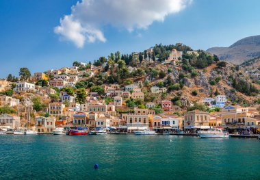 Symi, Yunanistan - 17 Ağustos 2017: Köy ve liman manzarası. Symi, sakin atmosferi ve muhteşem mimarisi ile ziyaretçileri hayrete düşüren küçük bir Dodecanese adasıdır.. 
