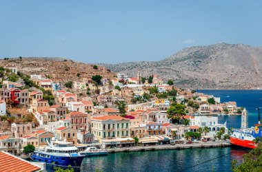 Symi, Yunanistan - 17 Ağustos 2017: Köy ve liman manzarası. Symi, sakin atmosferi ve muhteşem mimarisi ile ziyaretçileri hayrete düşüren küçük bir Dodecanese adasıdır.. 