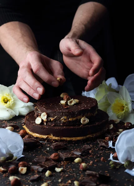 Pastel de chocolate en un plato, que está decorado con avellanas cocinero . — Foto de Stock