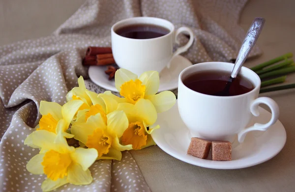 Tazas de té y un brazo lleno de narcisos . — Foto de Stock