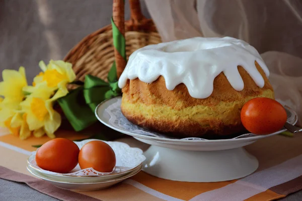 Velikonoční dort, malovaná vajíčka a kytice narcisů. — Stock fotografie