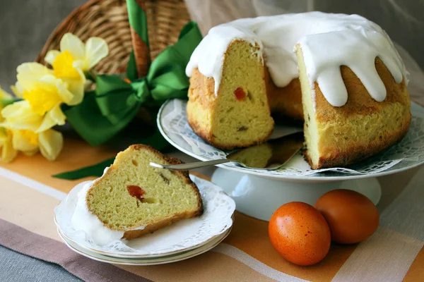 Torta di Pasqua, tagliata a pezzi su un piatto e uova dipinte sul tavolo . — Foto Stock