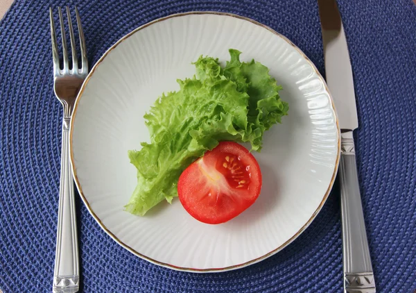 Lechuga y tomate acostados en un plato blanco . — Foto de Stock