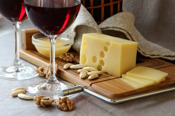 Шматок сиру на дошці, келихи для вина та горіхи . — стокове фото