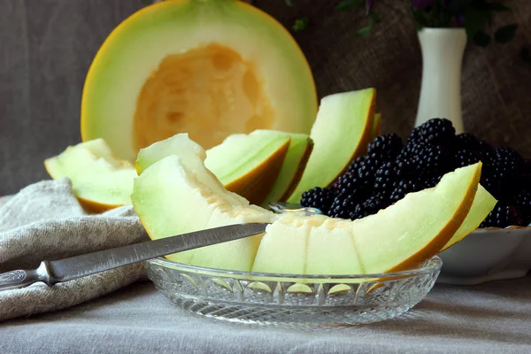 Ripe slices of melon and a plate with blackberries. — Stock Photo, Image
