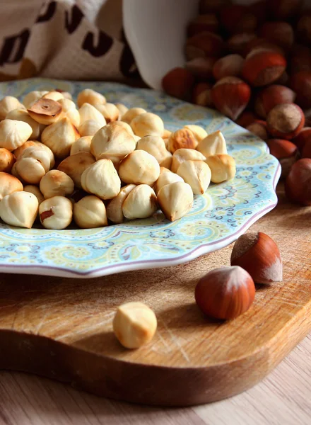 Peeled hazelnuts on a plate and nuts in the shell. — Stock Photo, Image