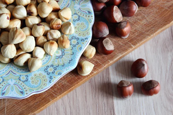 Peeled hazelnuts on a plate and nuts in the shell. — Stock Photo, Image