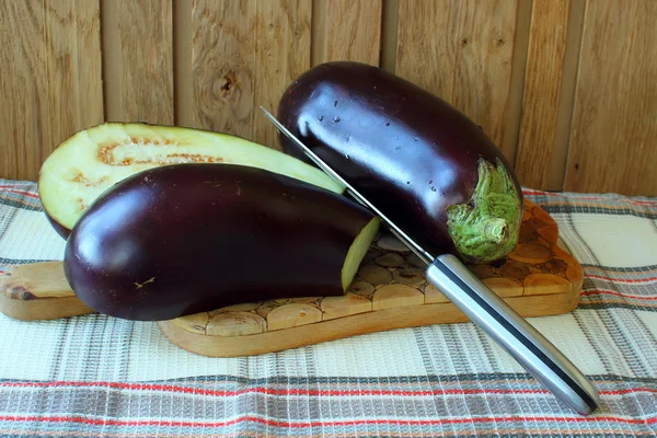 Aubergine cut in half and a knife — Stock Photo, Image