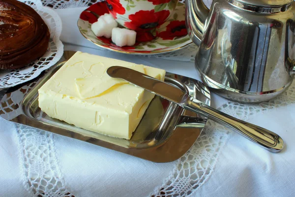 Mantequilla en el plato de mantequilla y cuchillo en un mantel blanco — Foto de Stock